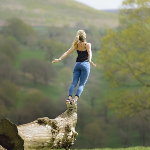 Image of woman standing on a log in the sunshine