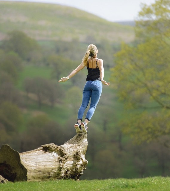 Image of woman standing on a log in the sunshine